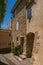 View of typical stone houses with sunny blue sky, in a raised alley of Lourmarin.