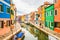 View on typical street scene showing brightly painted houses and boats with reflection along canal