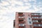 View from underneath on colorful pink apartment building in front of blue sky with clouds. City dwelling. Urban architecture