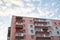 View from underneath on colorful pink apartment building in front of blue sky with clouds. City dwelling. Urban architecture