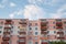 View from underneath on colorful pink apartment building in front of blue sky with clouds. City dwelling. Urban architecture