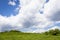 View up a hill with vast blue sky and large clouds, creative copy space opportunity