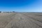 View up a huge empty beach with tire tracks towards several large buildings in the distance