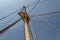 View up the main mast of a large sailing vessel, rigging and shrouds fanning out against a dark sky