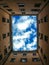 A view up to the blue sky from an Italian courtyard surrounded by houses