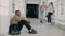 View of upset serious african-american male student sitting on floor in white spacious university corridorwhile his