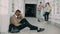 View of upset serious african-american male student sitting on floor in white spacious university corridorwhile his