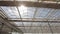 View of upwards through the top of industry greenhouse, watering lines and lighting equipment in a nursery for growing