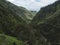 View of valley with green mountains and tropical plants, at hiking trail Levada do moinho to levada nova waterfall