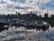 View of Vancouver marina at seawall with yacht boats and downtown skyscrapers mirrored in the calm water of the basin.