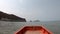 View video on a boat driving in the sea with sea waves Background island and clouds in the bright sky