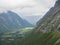 View from viewpoint platform on green valley and massif Trolltindene in Romsdal valley, Norway. Cloudy white sky clouds.