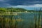 View on the village with dock along the lake shore with dark blue cloudscape, El Remate, Peten, Guatemala