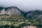 View of the village high in the mountains. Thick gray clouds cover the top. Highland Housing Concept. Olive plantations, houses