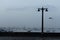 View of vintage Lamp posts on a street close to sea with boats and a bird flying