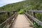View of walking across narrow wooden bridge in the wilderness