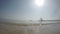 The view from water level of the sea beach on a breakwater with an arbor and the boat moving by the tropical sea, a wave