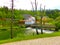 View on waterfall, mill in white building, pedestrian bridge in Park Postojna jama near Postojna Cave