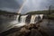 view of waterfall with rainbow, captured during stormy weather