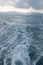 View of waves behind a boat and dramatic sky