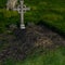 View of a well-kept grave in a large cemetery with a massive cross in the summer