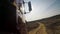 View from a wheel of the off-road truck riding in a dirt road on cloudy sky background. Scene. Close up for red cab of a