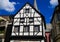 View on white medieval timbered house facade with catholic church clock tower in summer with blue sky