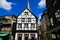 View on white medieval timbered house facade with catholic church clock tower in summer with blue sky