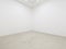 A view of a white painted interior of an empty room or an art gallery with a fluorescent lighting and concrete floors