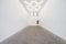 A view of a white painted interior of an empty room or an art gallery with a skylight lighting and concrete floors