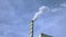 View of white smoke from chimney on blue sky background. Ecology and greenhouse effect concept