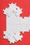 View of white unfinished jigsaw near connected puzzle pieces isolated on red