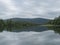 View of wide calm Tarra river from boat at Kvikkjokk, with forest and grass shore and green hills. Northern landscape in