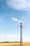 View of a wind power plant on a background of blue sky and fields with grain crops