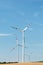 View of a wind power plant on a background of blue sky and fields with grain crops. The concept of environmental electricity produ