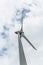 View of a wind turbine on top of mountains, cloudy sky as background