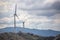 View of a wind turbines on top of mountains, cloudy sky as background