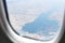 View from the window of the aircraft on the landscapes below, mountains, lakes, forests, seas. Aircraft window
