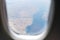 View from the window of the aircraft on the landscapes below, mountains, lakes, forests, seas. Aircraft window. The concept of tra
