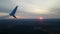 View from the window of the aircraft at sunset. The sun sets behind the horizon. Beautiful violet-pink shades of clouds.