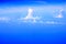 View of the window of airplane seeing  blue sky, white cloud and deep blue sea