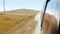 View from window moving car on dusty rural road with desert fields and hills