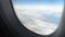 View through window of plane flying above clouds in peaceful sky, air transport
