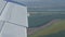 The view from the window of the porthole of a small passenger plane against a white wing. Top view of nature, river and