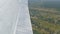The view from the window of the porthole of a small passenger plane against a white wing. Top view of nature, river and