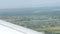 View from the window of a small passenger private plane against the backdrop of a white wing. Top view of houses, green