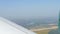 View from the window of a small passenger private plane against the backdrop of a white wing. Top view of houses, green