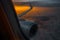 View from the window to airplane wing and engine at sunrise, flying above the clouds