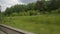 The view from the window of the train car. Rails, landscape, trees, summer sunny day