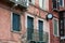 View of windows, balcony, clock and details of old cracked walls of buildings on the street in Venice, Italy